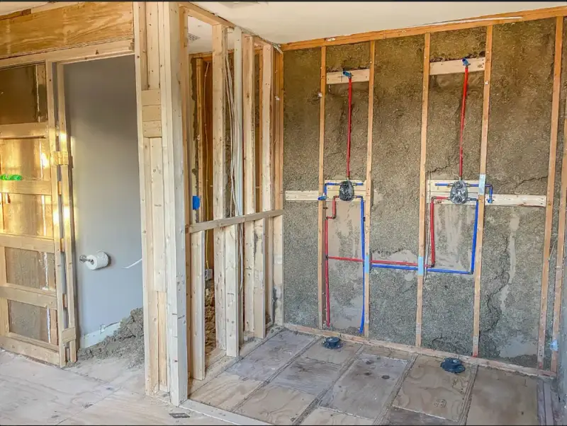 New PEX water lines and shower valves installed in an open framed wall during a bathroom remodel