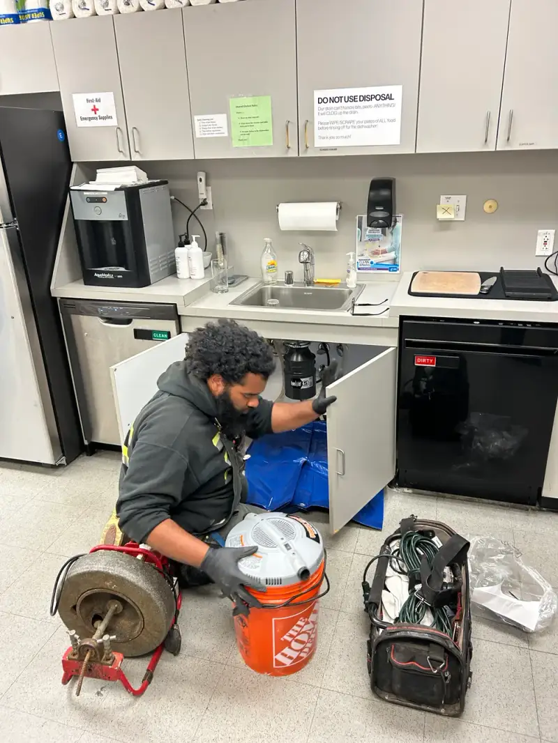All Phase technician using a professional drain cleaning machine on a clogged commercial sink line