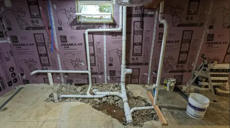 New PVC drain lines roughed in through a basement concrete slab for a bathroom addition